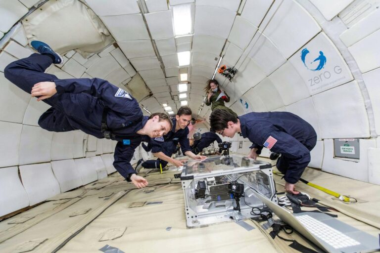 researchers working on the black box extrusion process smile as they hover above the box in low-gravity on a flight test