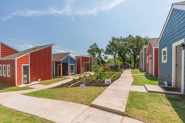 a neighborhood of tiny blue and red houses with a green lawn